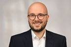 Dennis Welter hat eine Glatze und einen Dreitagebart, er trägt eine Brille und einen Anzug