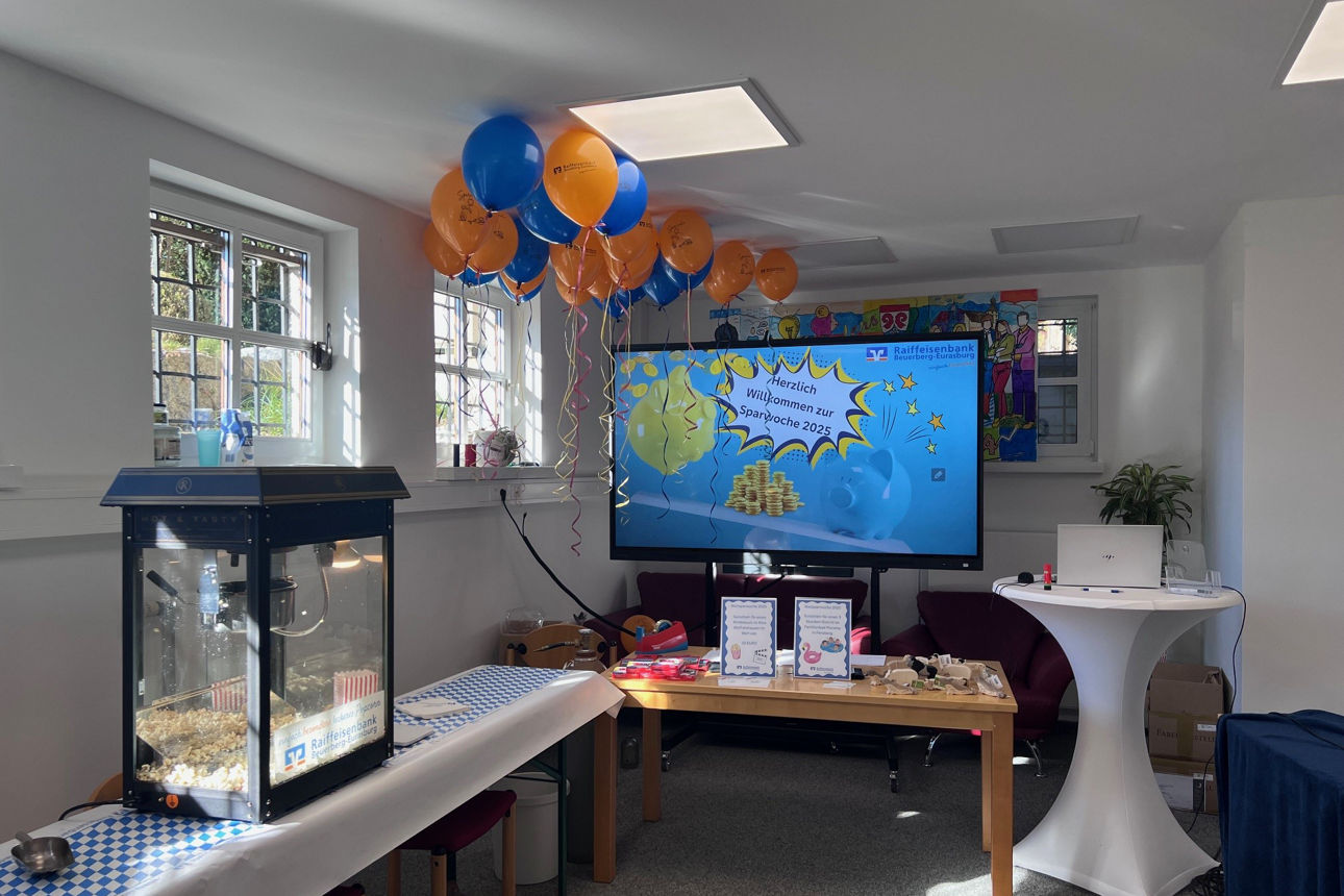 Der Kinderschalter in der Weltsparwoche 2025 mit einem Monitor, Luftballons, Popcorn und Geschenken. 