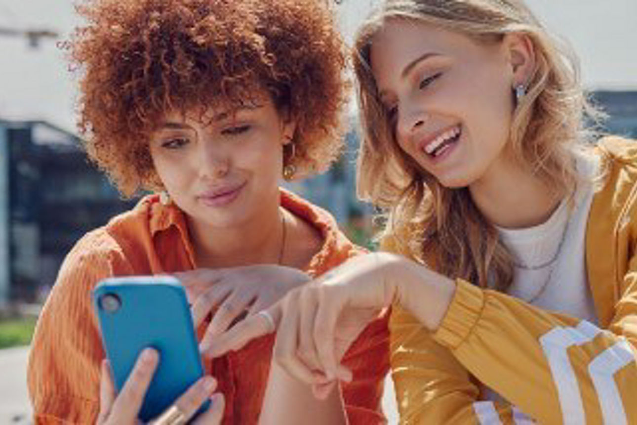 zwei junge Frauen schicken sich über wero Geld über das Smartphone