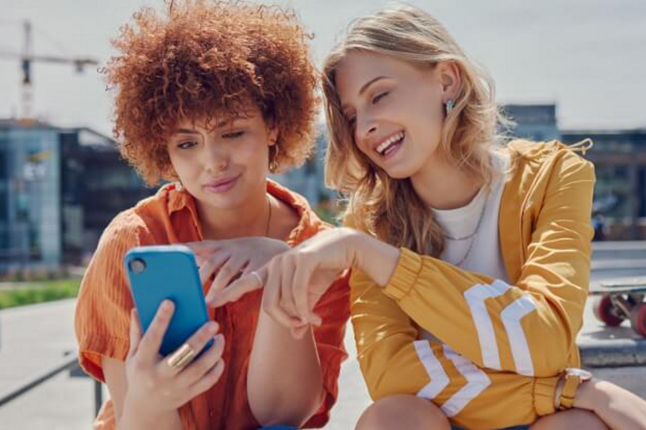 Zwei Frauen schauen lächelnd auf ein Handy