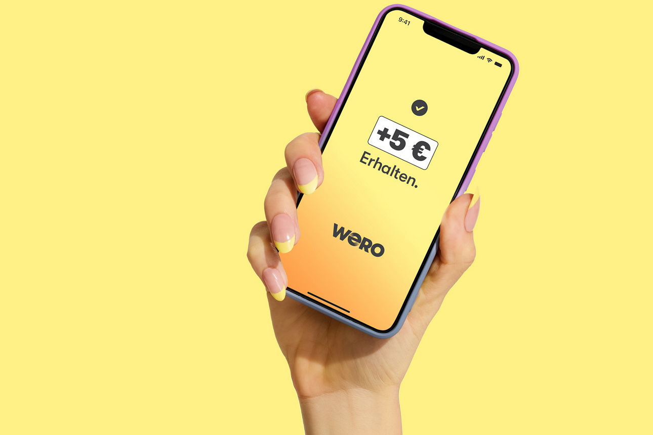 Hand mit Handy vor gelbem Hintergrund