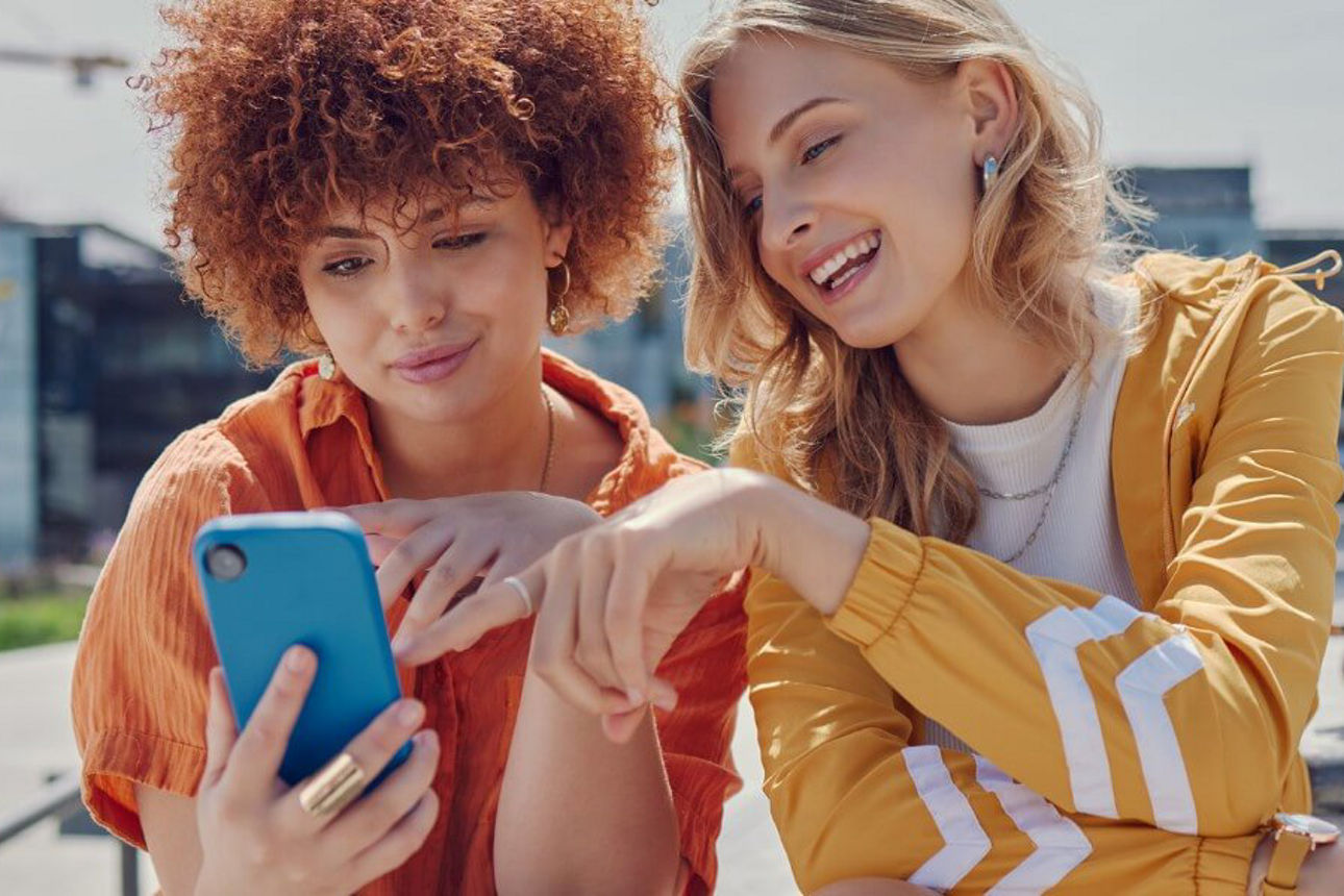 Zwei Frauen schauen lächenld auf ein Handy