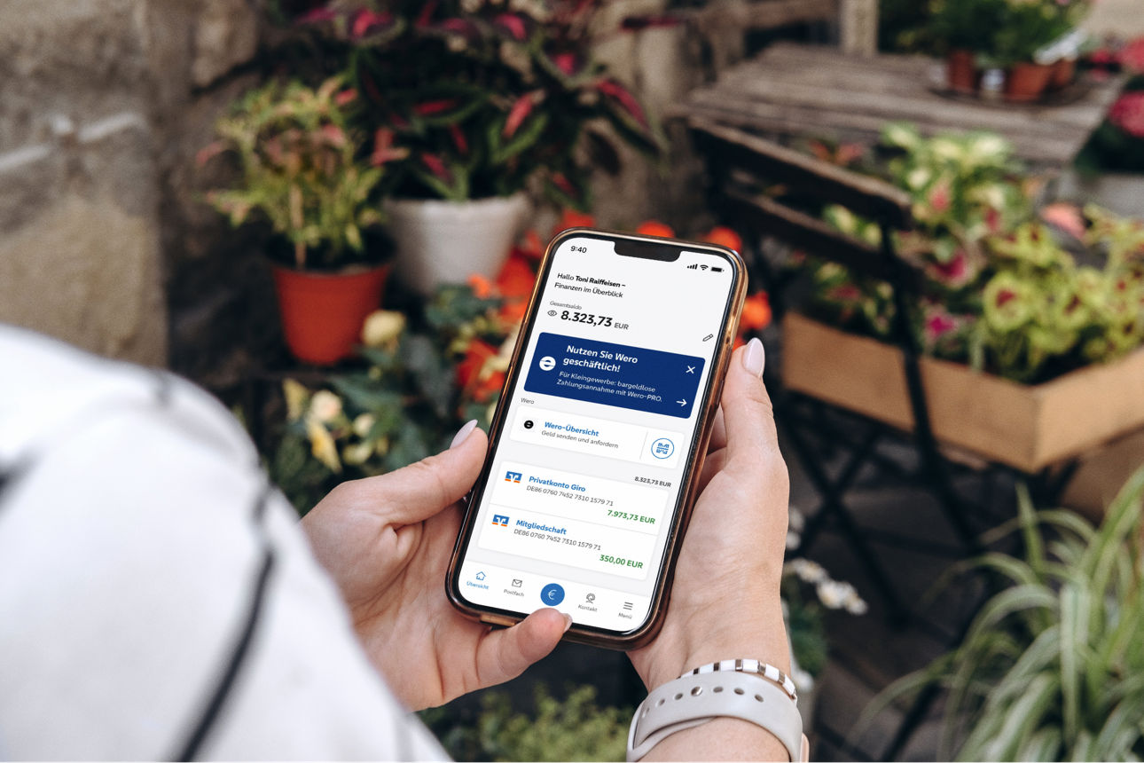 Eine Frau hält ihr Smartphone in den Händen, in der eine Banking App zu sehen ist.