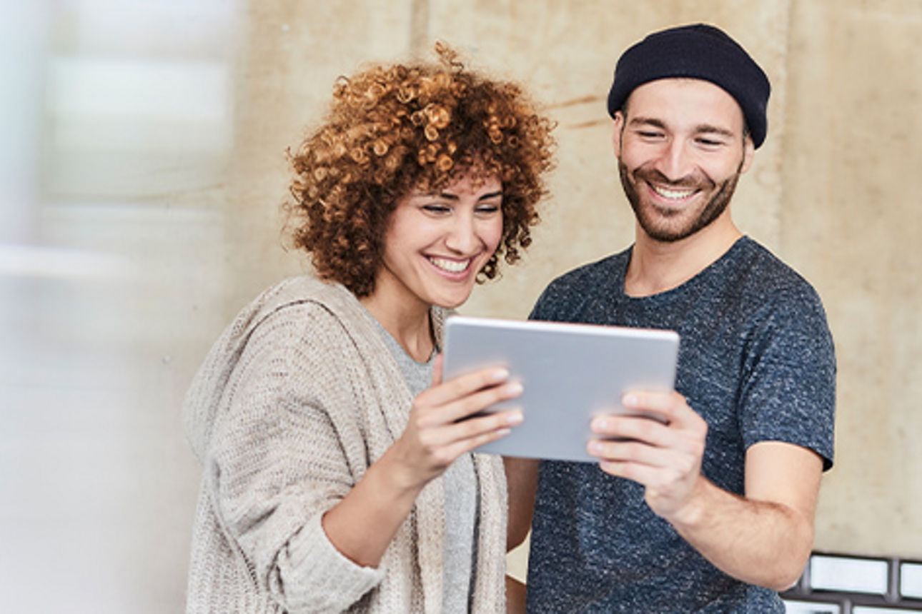 Ein Mann und eine Frau schauen auf ein Tablet