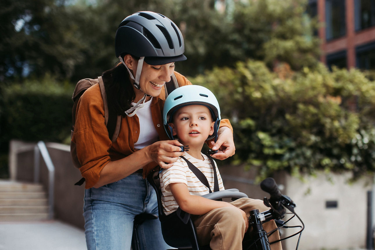 Mutter setzt ihrem Sohn einen Fahrradhelm auf den Kopf