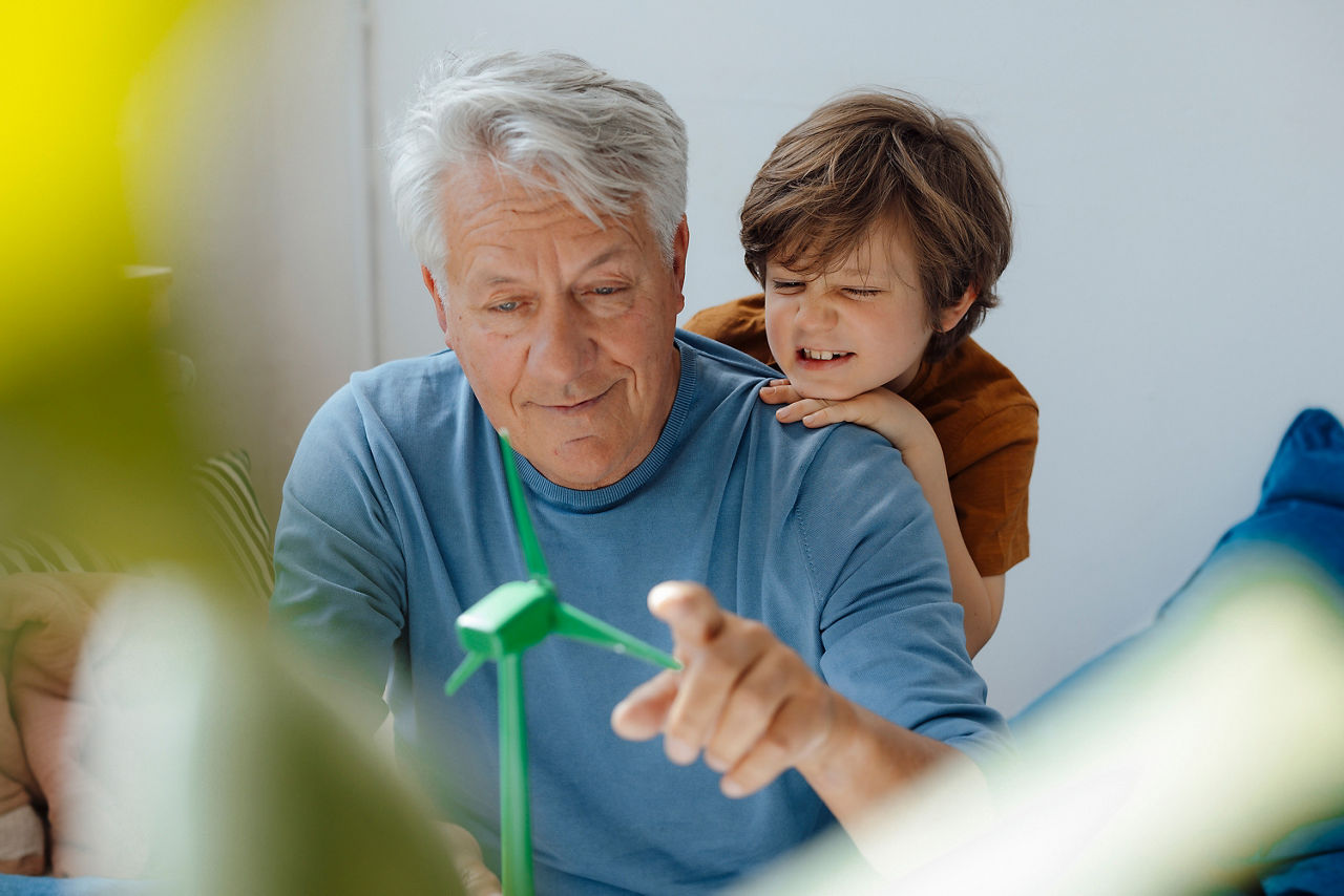Großvater und Enkel untersuchen das Modell einer Windkraftanlage zu Hause