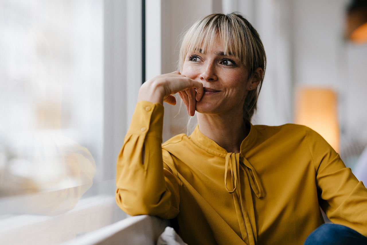 Porträt einer schönen blonden Frau, die aus dem Fenster schaut