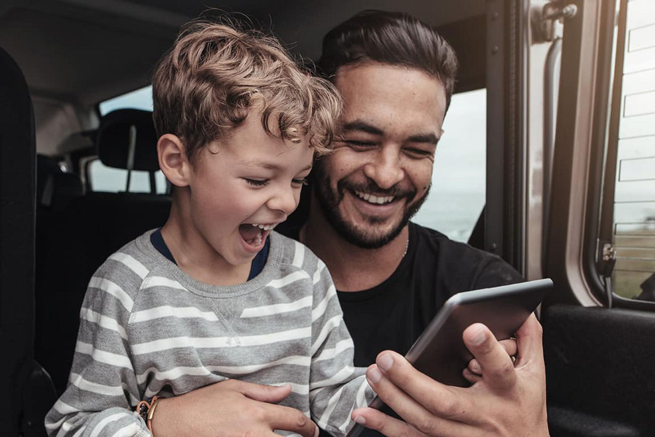 Ein Vater zeigt seinem Sohn etwas auf dem Mobiltelefon