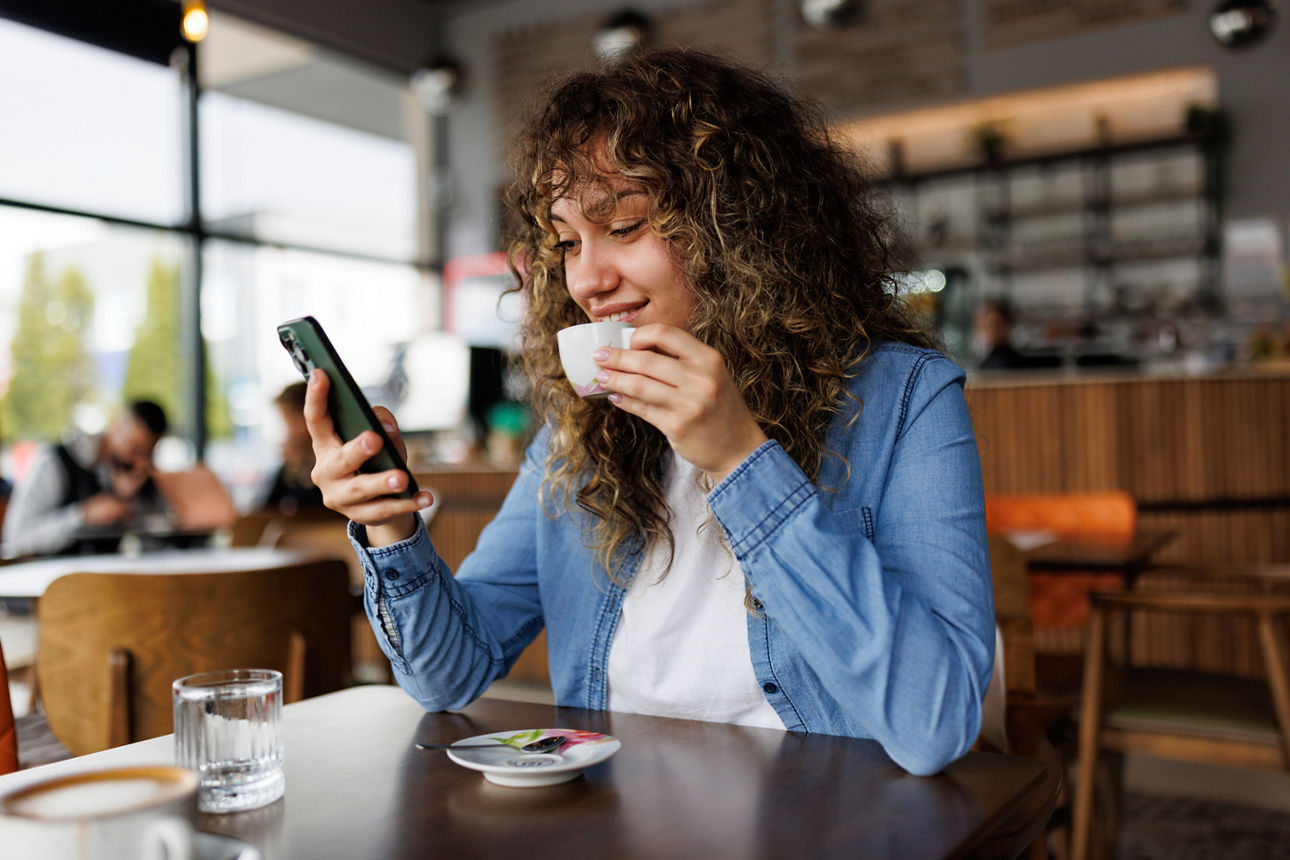 Glückliche junge Frau mit Handy und Kaffee im Café genießen - Stock-Fotografie