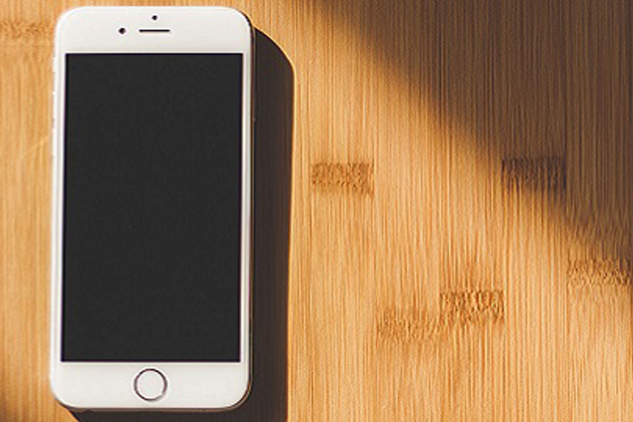 Einfaches, elegantes Design eines weißen Smartphones auf einem Tisch aus Bambusholz