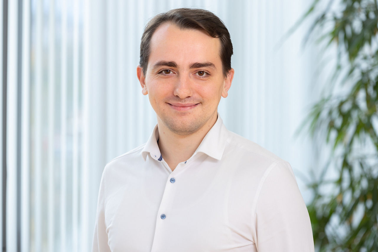 Ein Mann mit Anzug mit einem Büro im Hintergrund. 