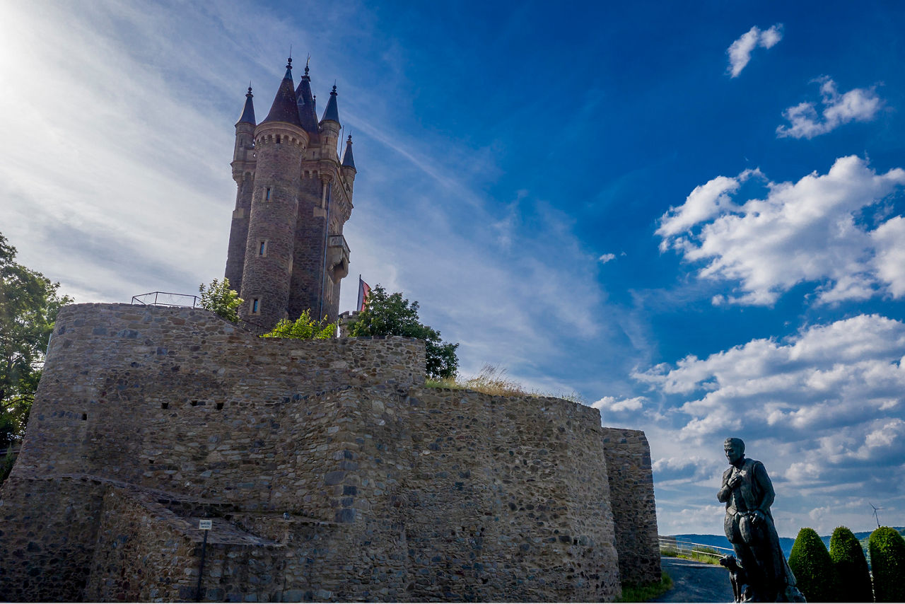 Eine Burg auf einem Hügel vor blauem Himmel 