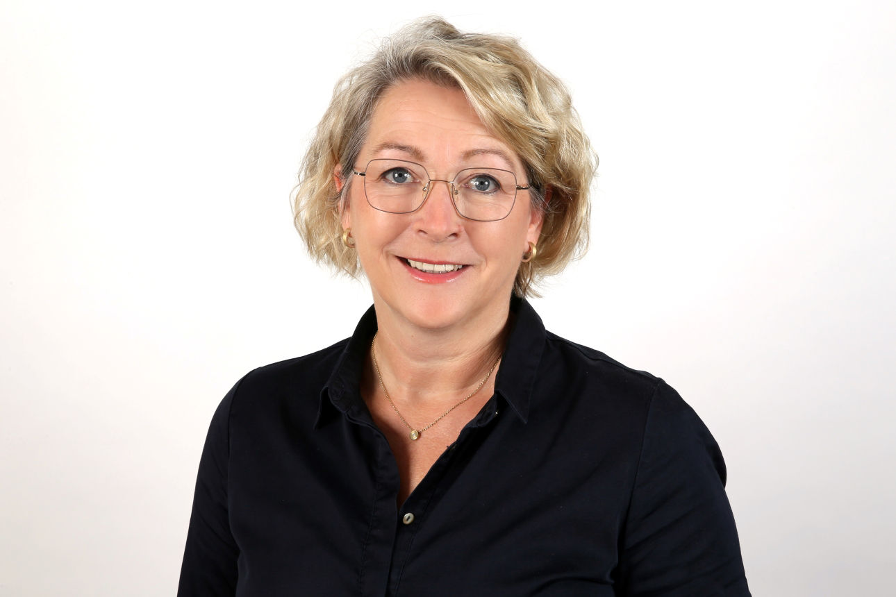 Eine lächelnde Frau schaut in die Kamera.v