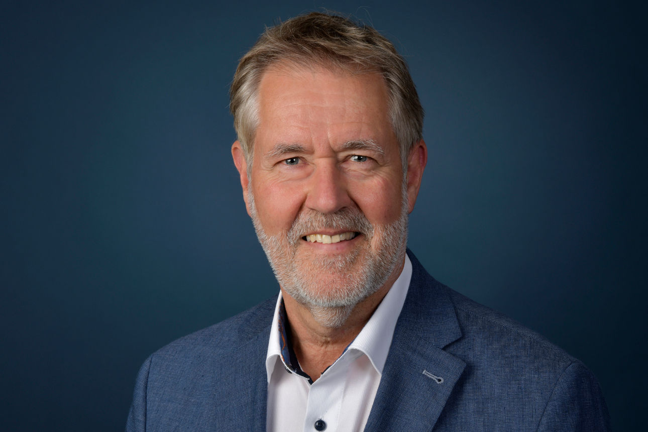 Ein Mann im Anzug, der in die Kamera lächelt