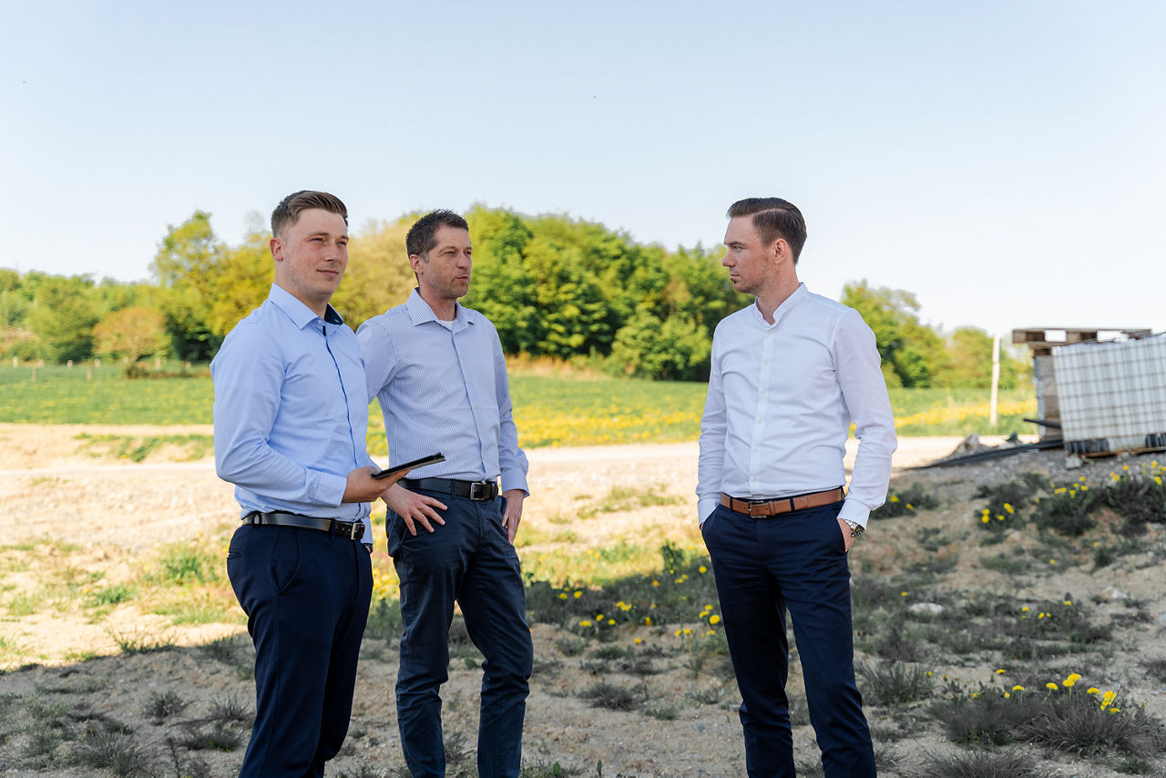 Drei Personen, die auf einer sandigen Wiese laufen