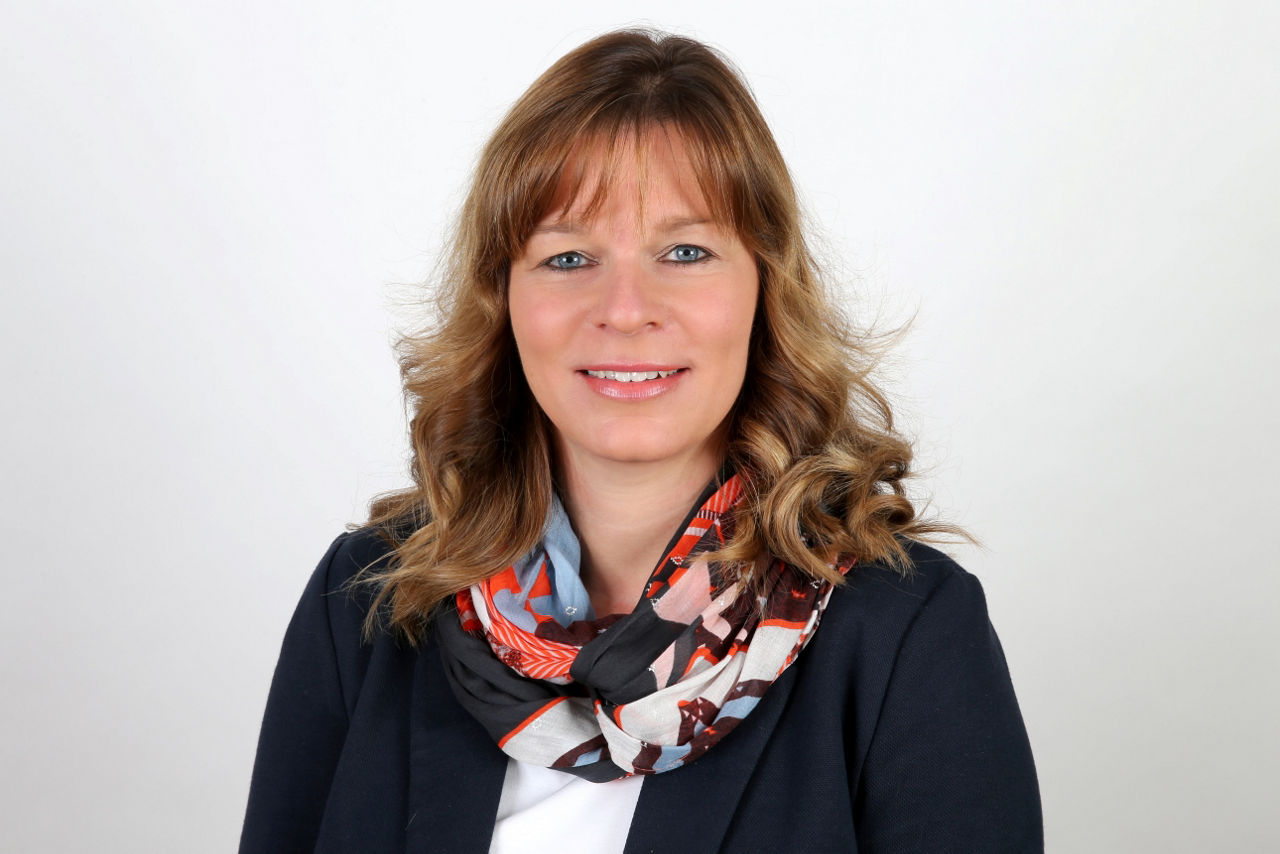 Eine lächelnder Frau schaut in die Kamera.