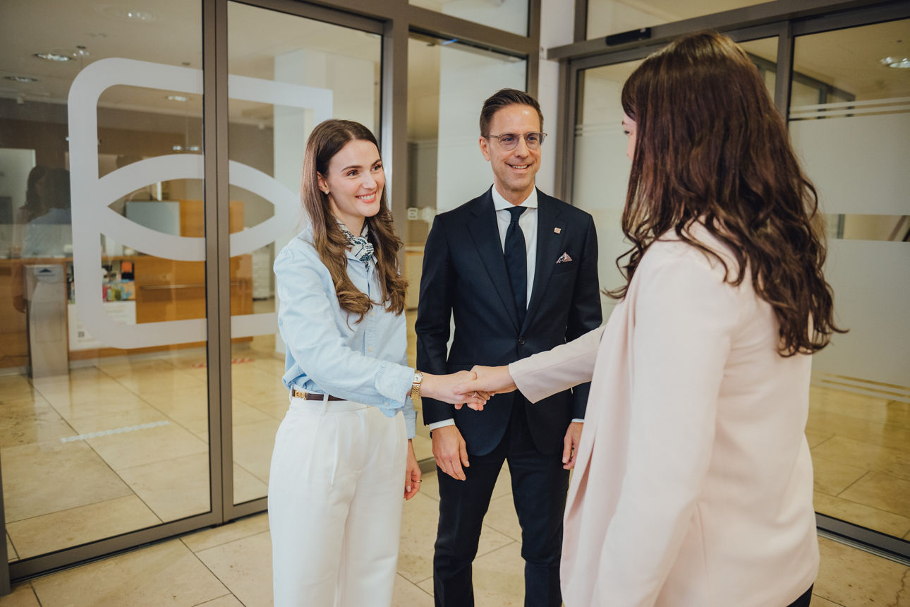 Eine junge Frau lacht und gibt einer anderen Frau die Hand