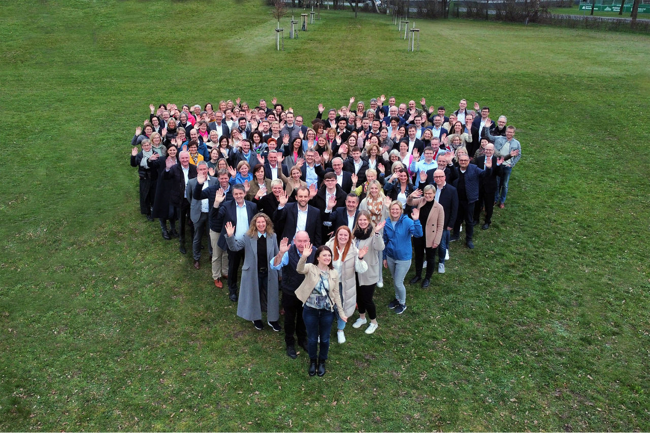 Gruppenfoto: Mitarbeiter in Herzform aufgestellt