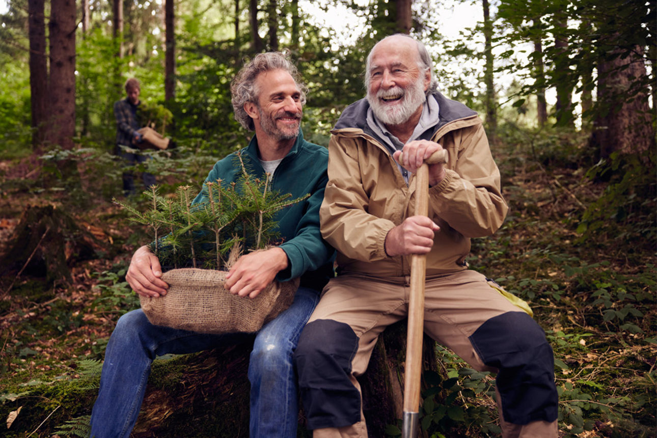 Männer sitzen lachend im Wald