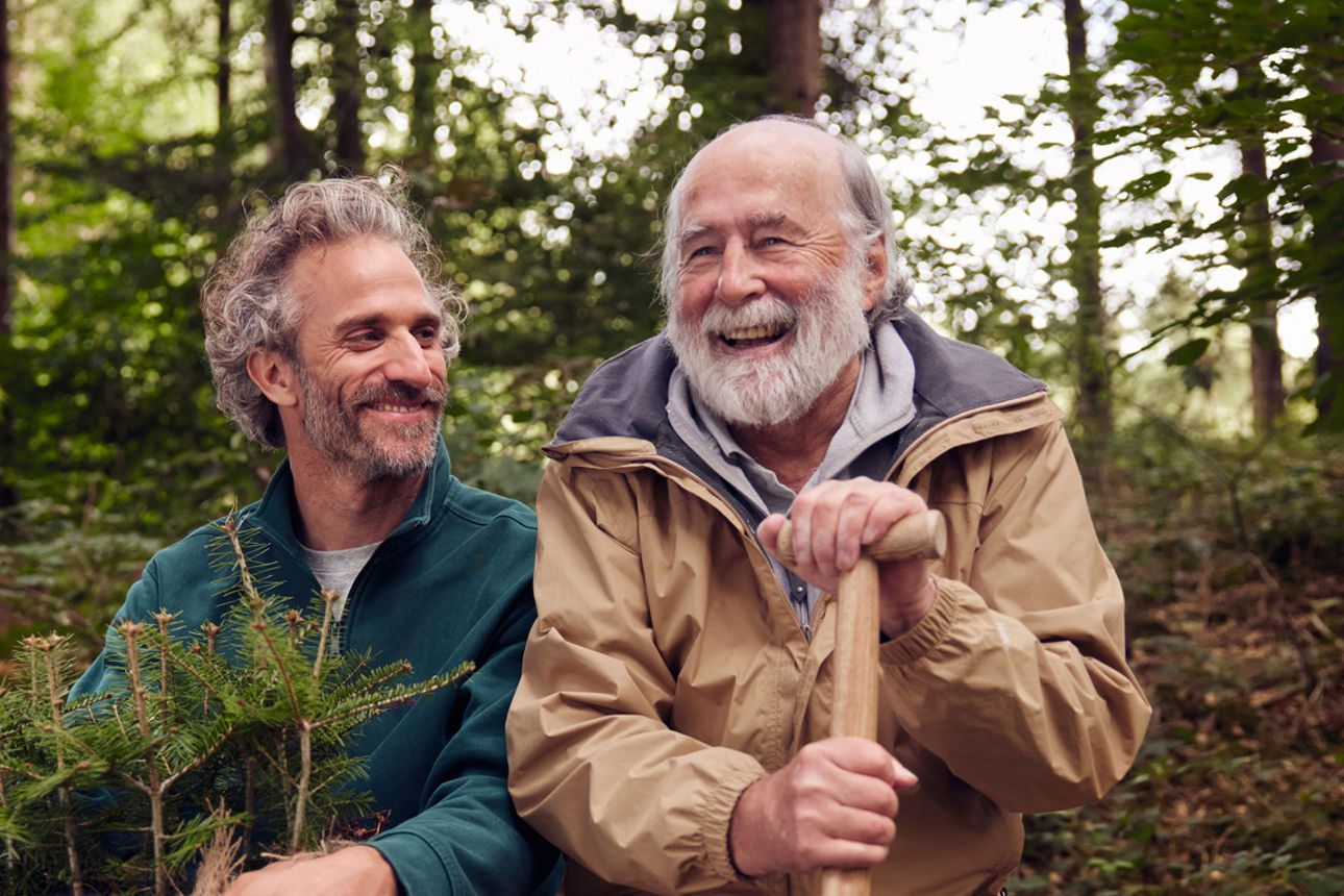 Lachender Mann mit Notebook in den Bergen