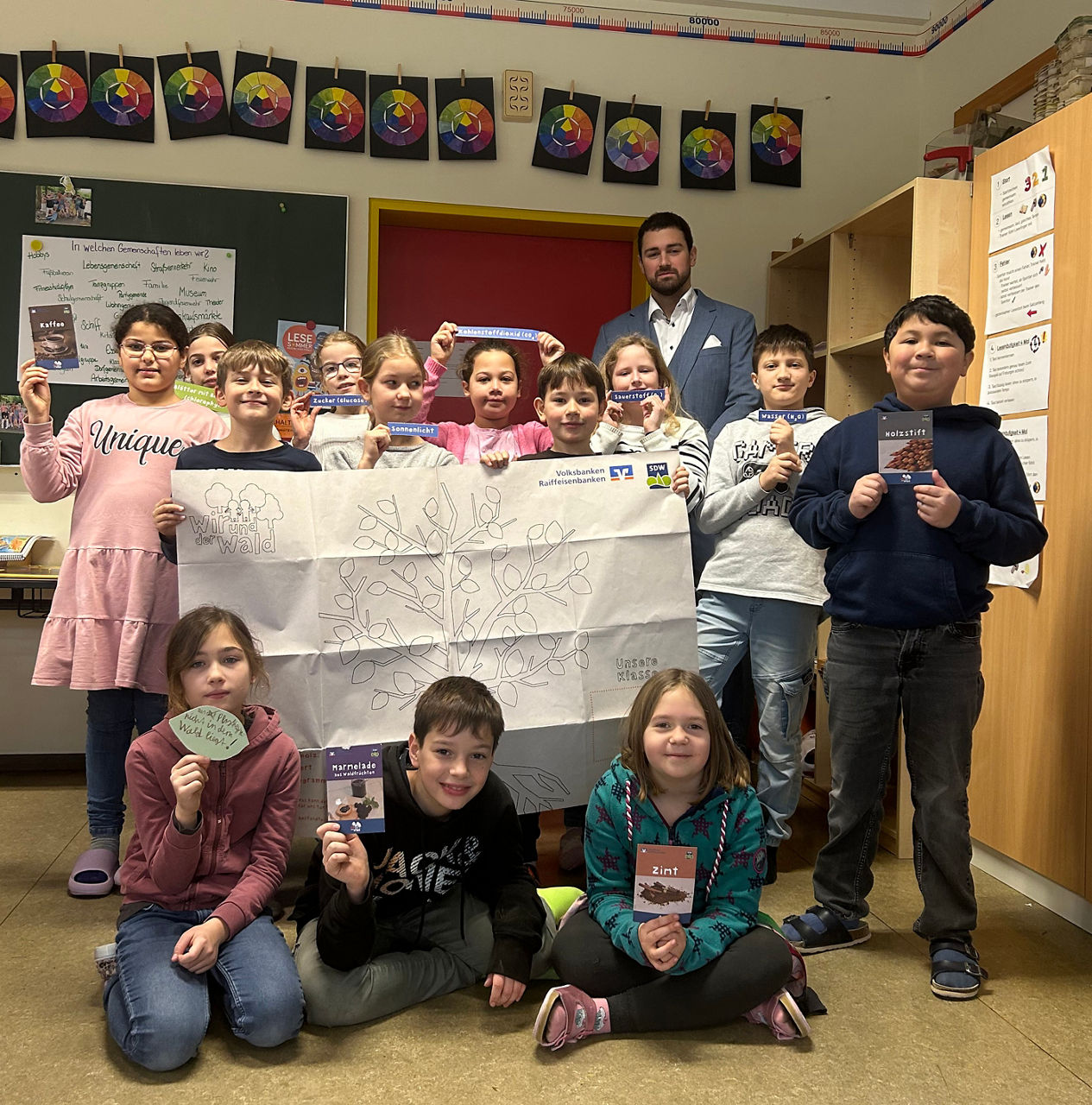 Viele Kinder halten ein Großes Blatt Papier in der Hand.