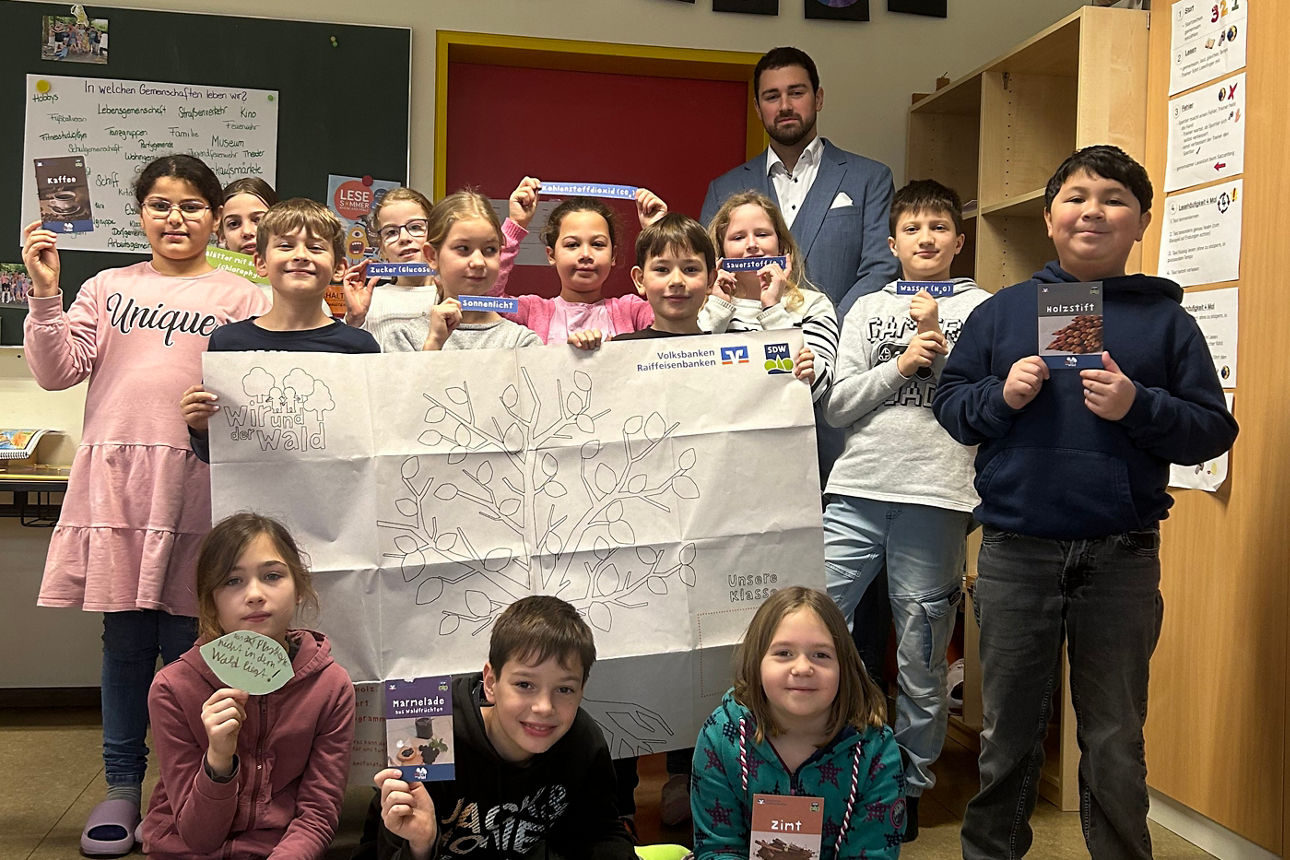 Viele Kinder halten ein Großes Blatt Papier in der Hand. 