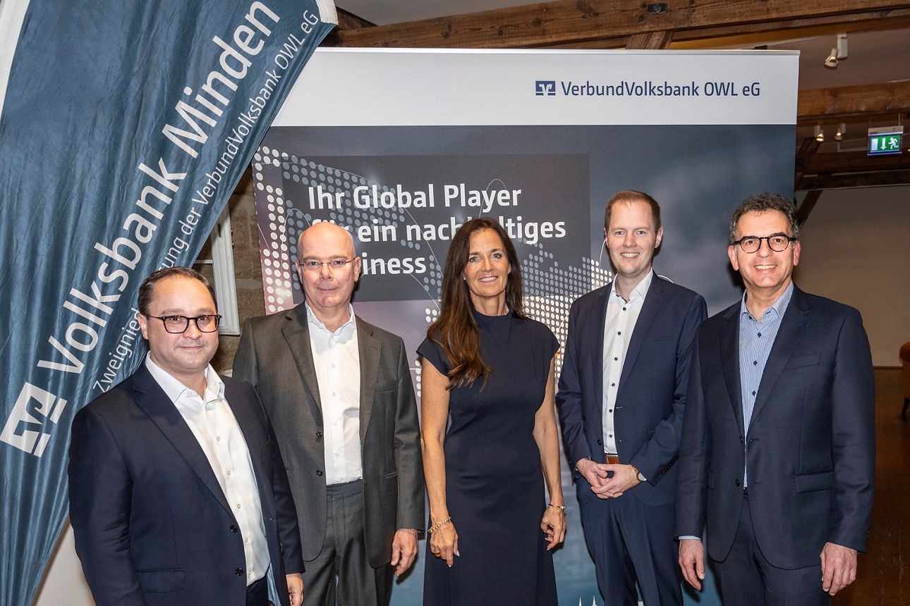 Eine Gruppe von Menschen vor einem Werbe-Rollup der Volksbank Minden