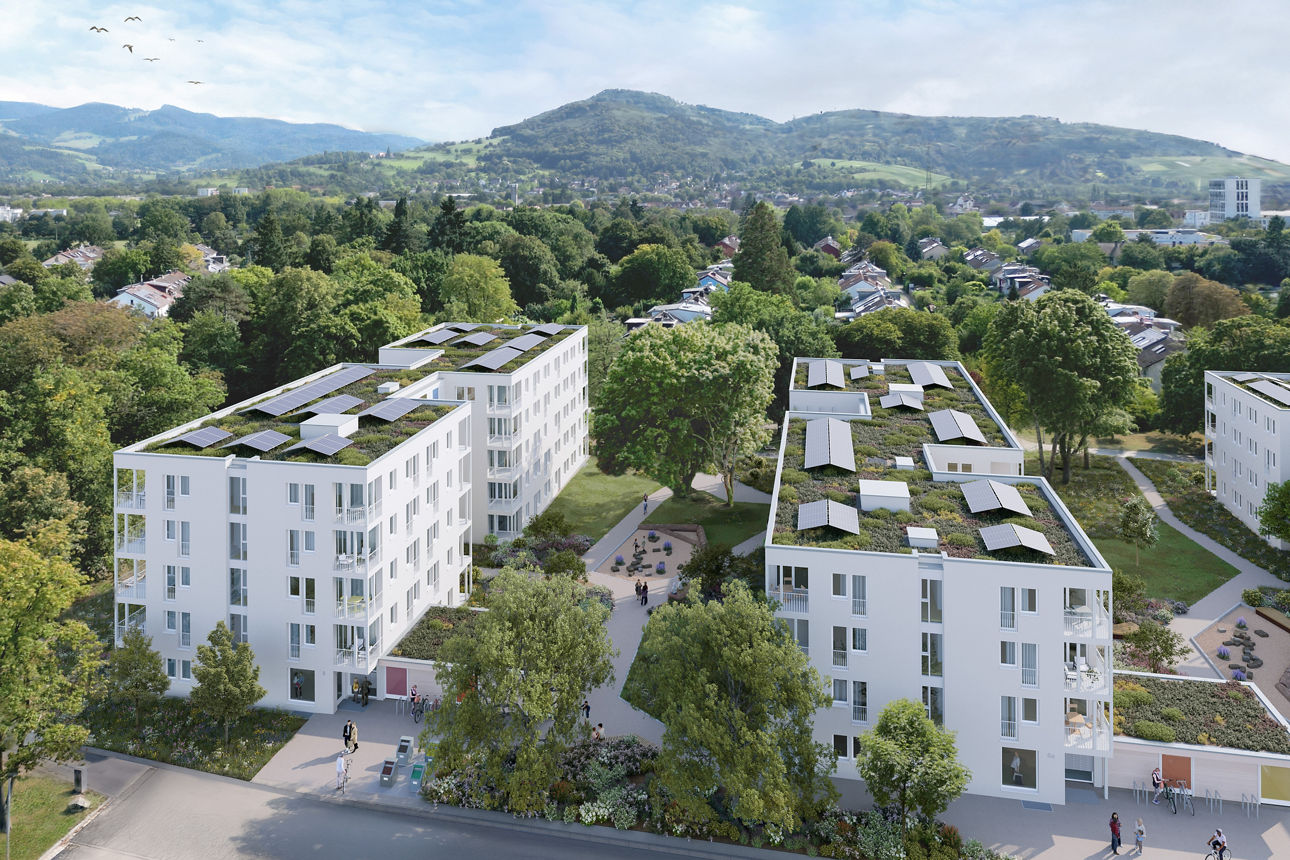 Luftaufnahme einer modernen Wohnanlage mit begrünten Dächern, Wegen, Bäumen und weitem Blick in die hügelige Landschaft.