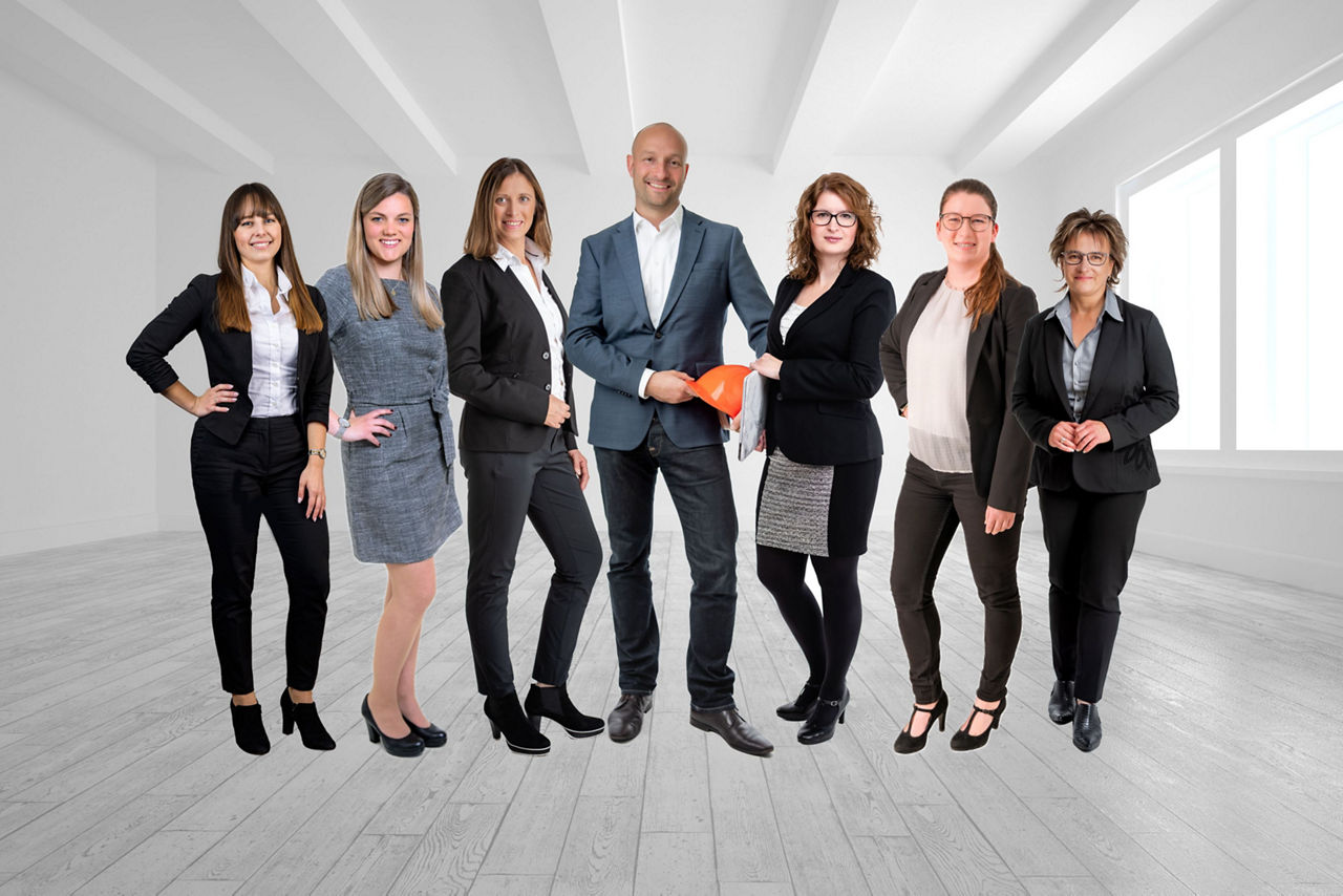 Unsere Ansprechpartner aus dem Bereich Wohnbau: 6 Frauen und 1 Mann in der Mitte in Businesskleidung