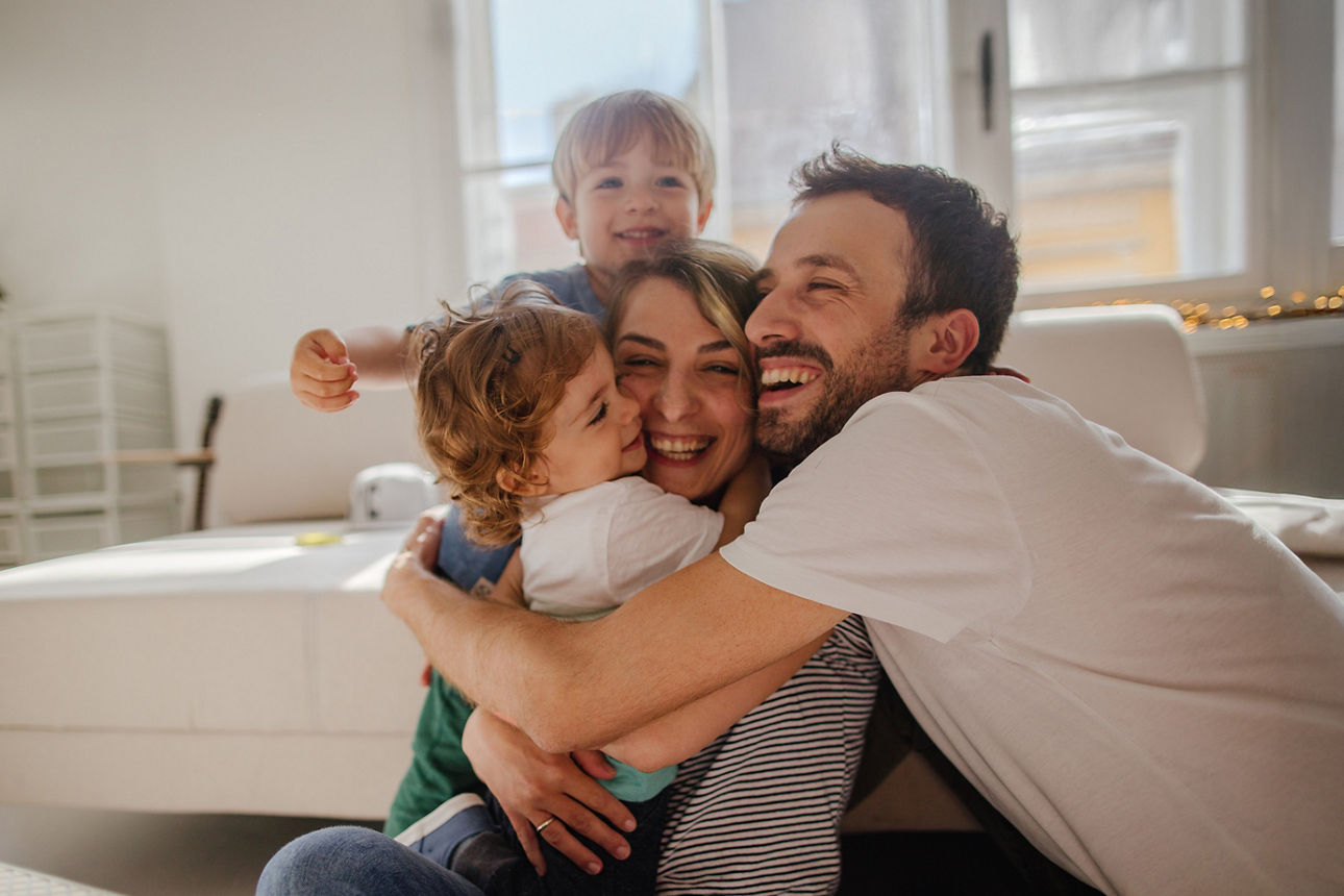 Eine vierköpfige Familie hält sich in den Armen und lachen