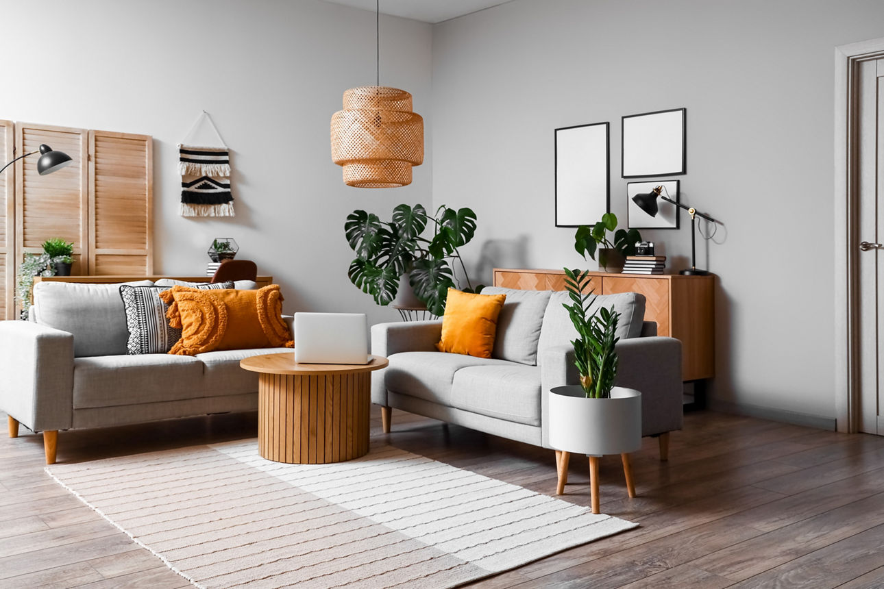 Wohnzimmer mit zwei grauen Sofas und orangenen Kissen