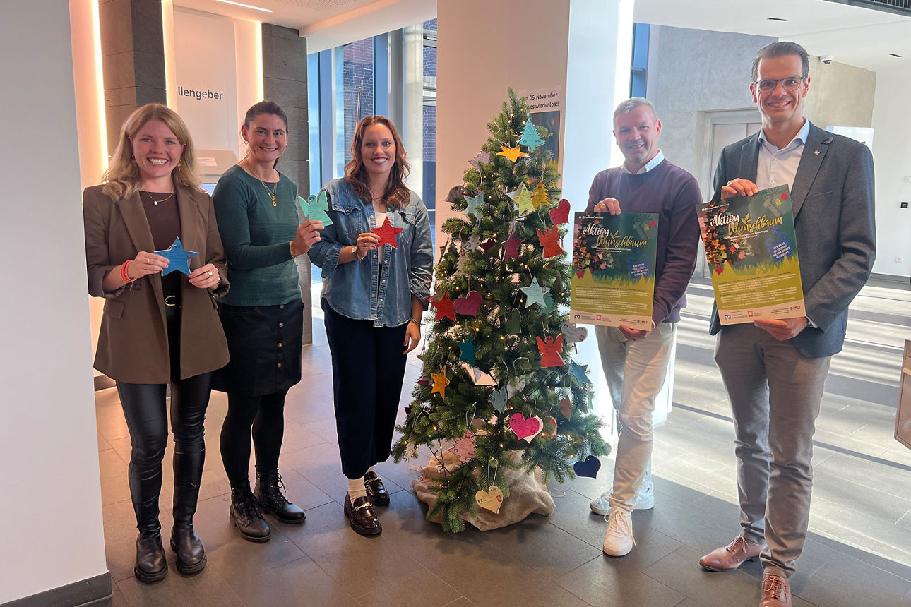 Fünf Personen stehen um Weihnachtsbaum in der Bank