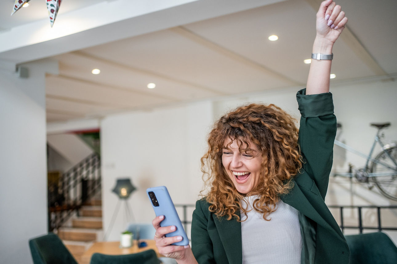 Frau schaut auf Handy und freut sich