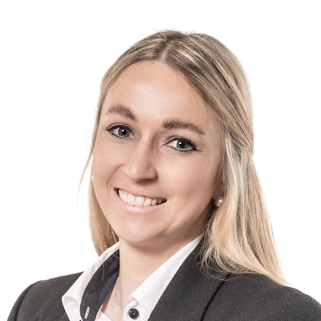 Mitarbeiterin Annika Fuchs in Business Kleidung mit blauem Schal. Sie lächelt in die Kamera.