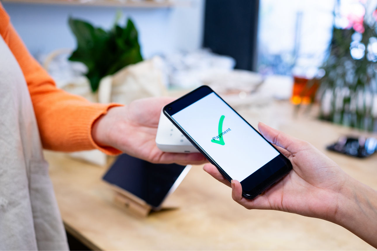 Kunde bezahlt kontaktlos mit seinem Mobiltelefon im Supermarkt.