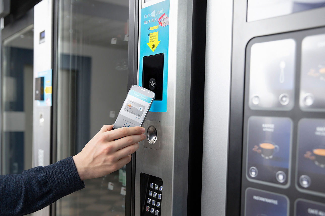 Jemand zahlt an einem Getränkeautomaten mit dem Smartphone