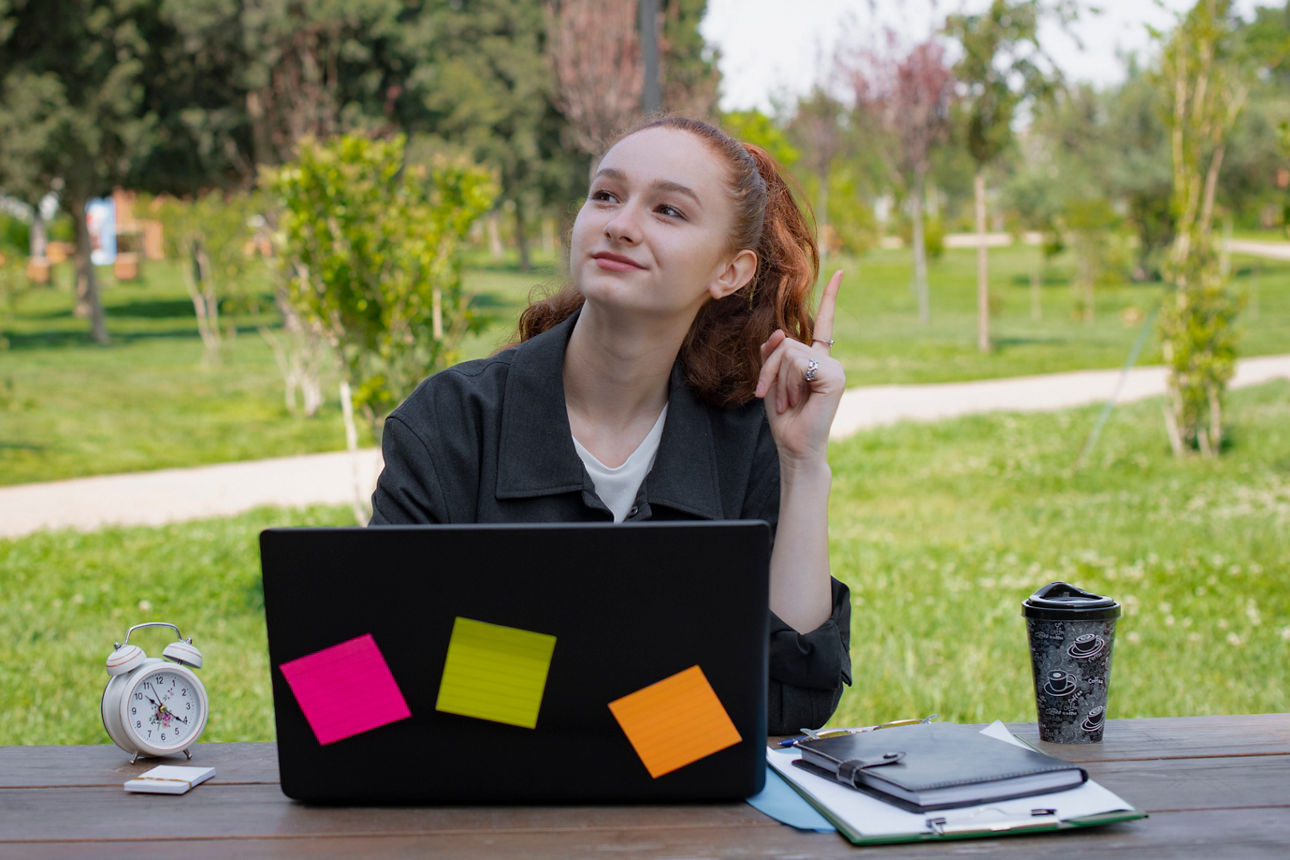 Frau mit Laptop am Tisch im Garten