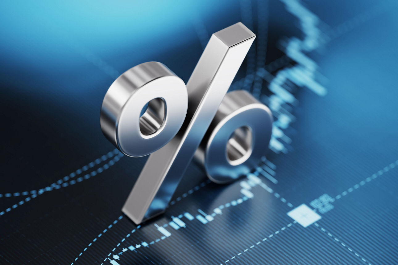 Metallisches Prozentzeichen vor digitalem Finanzdiagramm.