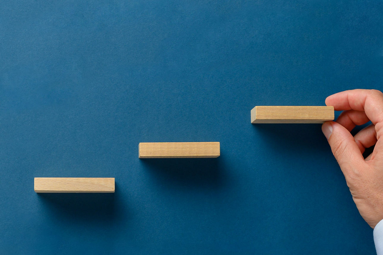 Treppe aus Holzbauklötzen auf blauem Grund