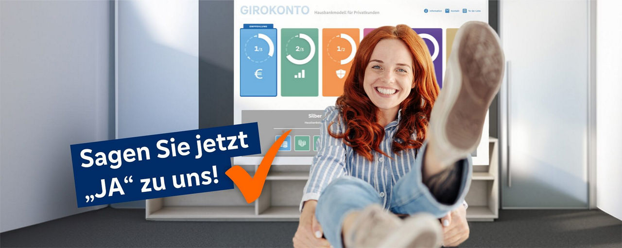 Frau im Vordergrund hebt den linken Fuß hoch, im Hintergrund das Hausbankmodell auf dem Fernseher