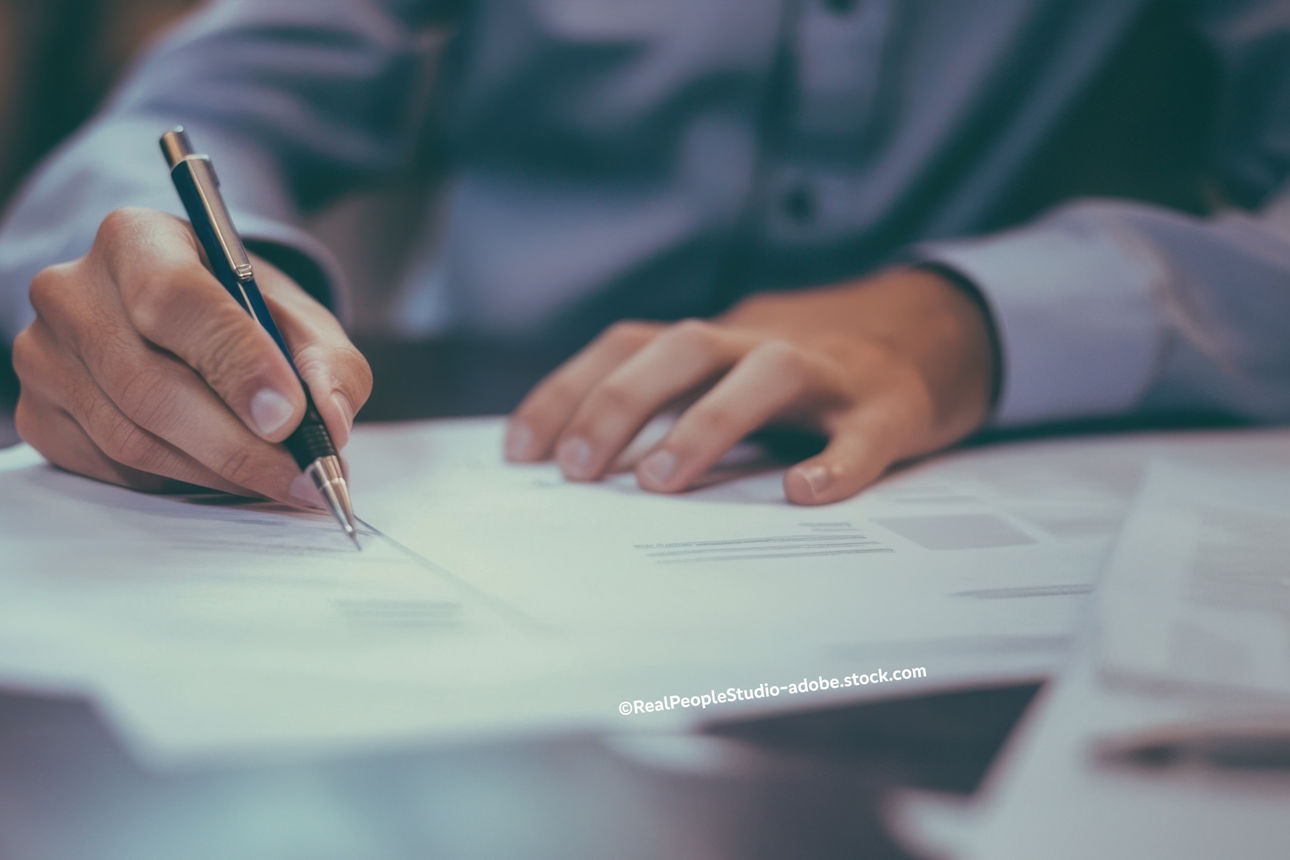 Mann unterschreibt auf einem Papier