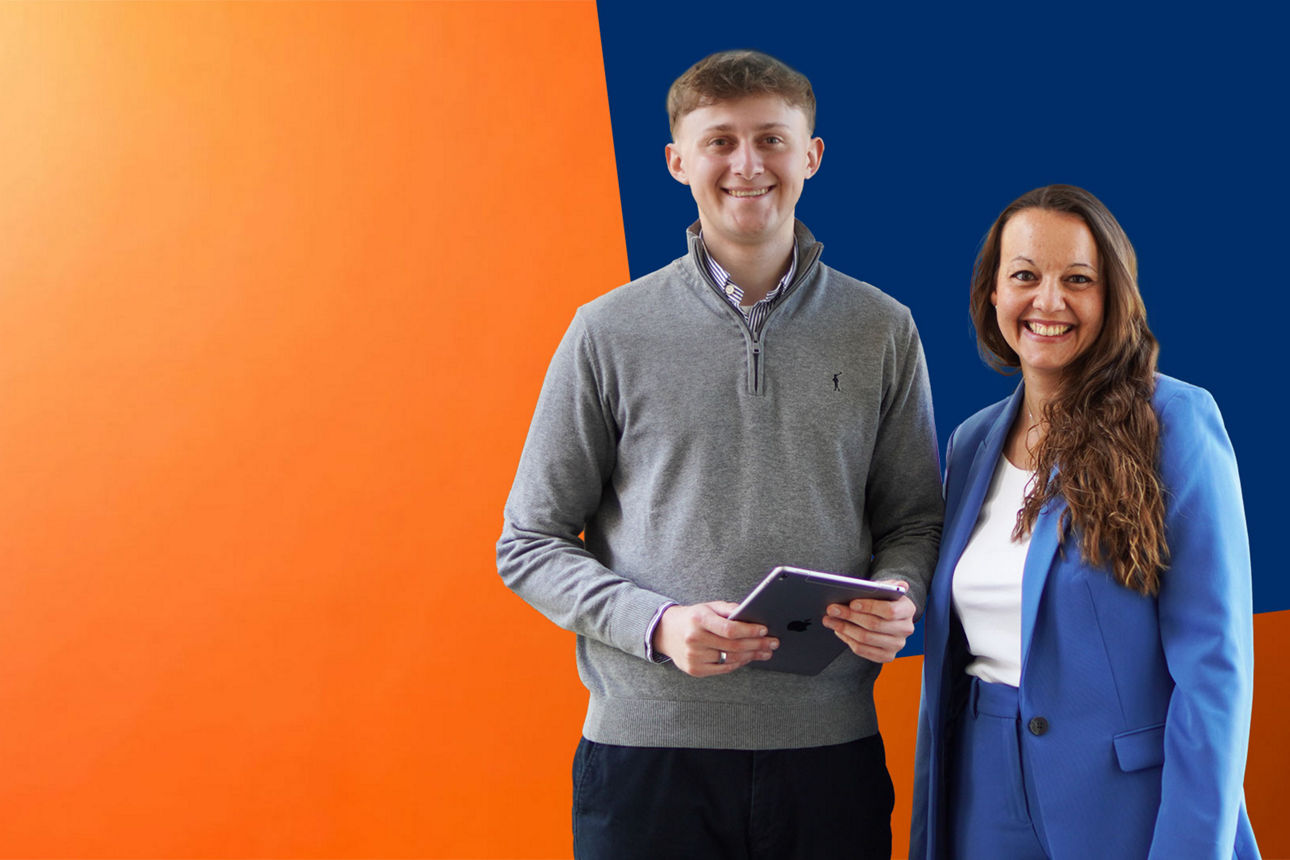 Zwei Mitarbeiter stehen vor orange-blauer Wand