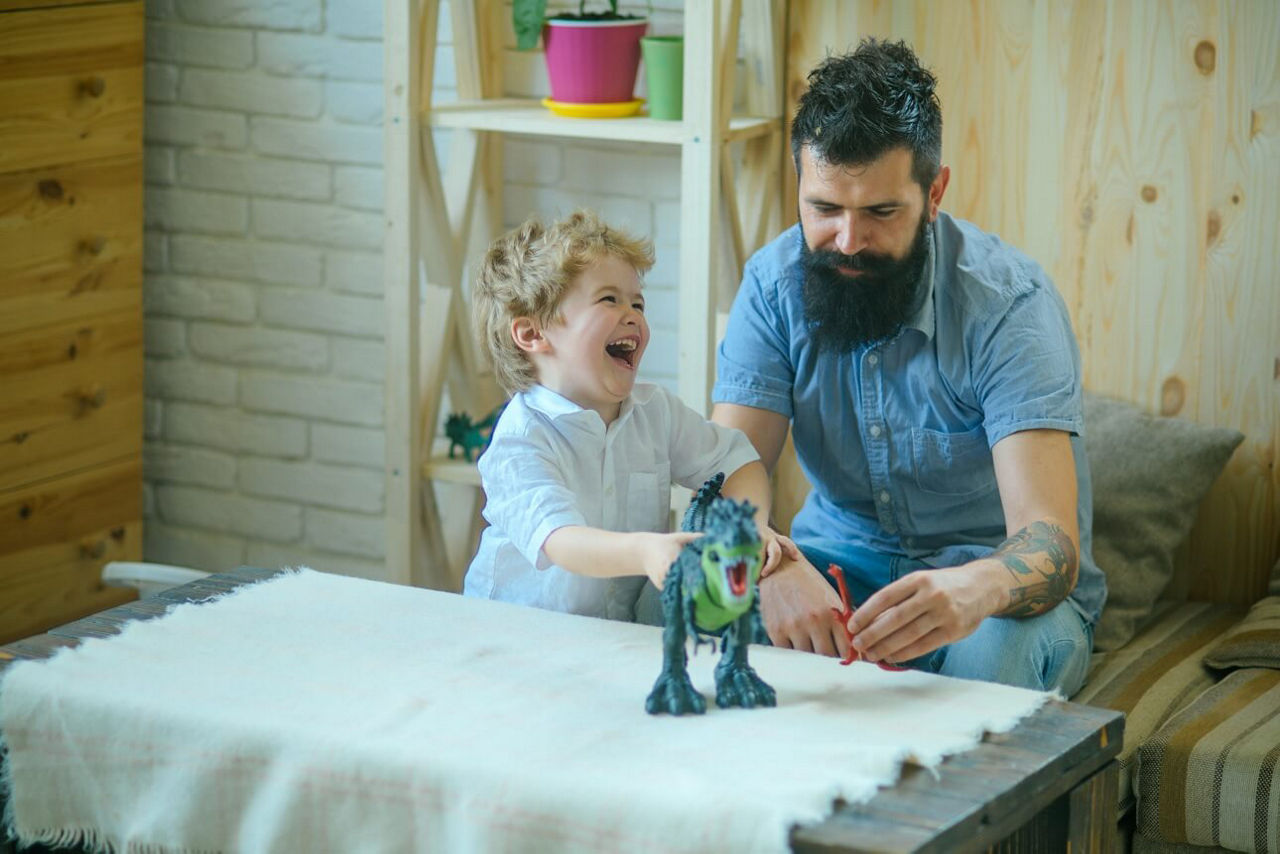 Junge und Vater spielen mit einem Dinosaurier