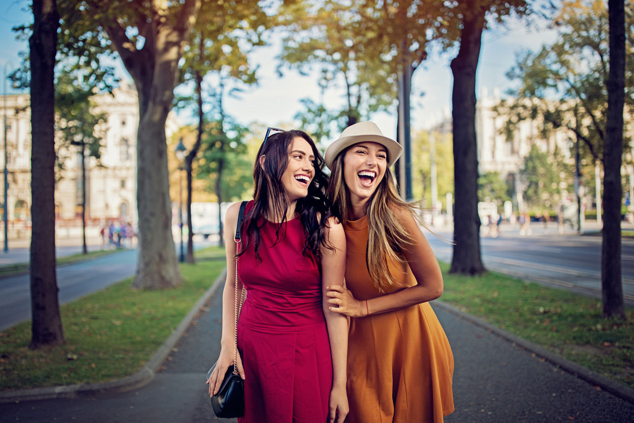 Happy girlfriends are walking and hugging in the city and make fun together