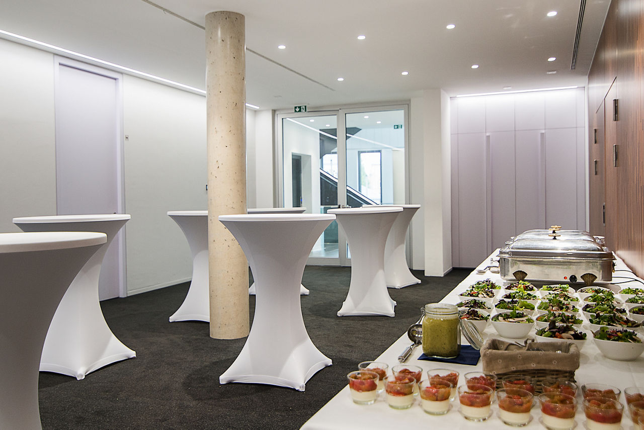 Tische mit Cateringbuffet, davor mehrere Stehtische mit weißen Hussen