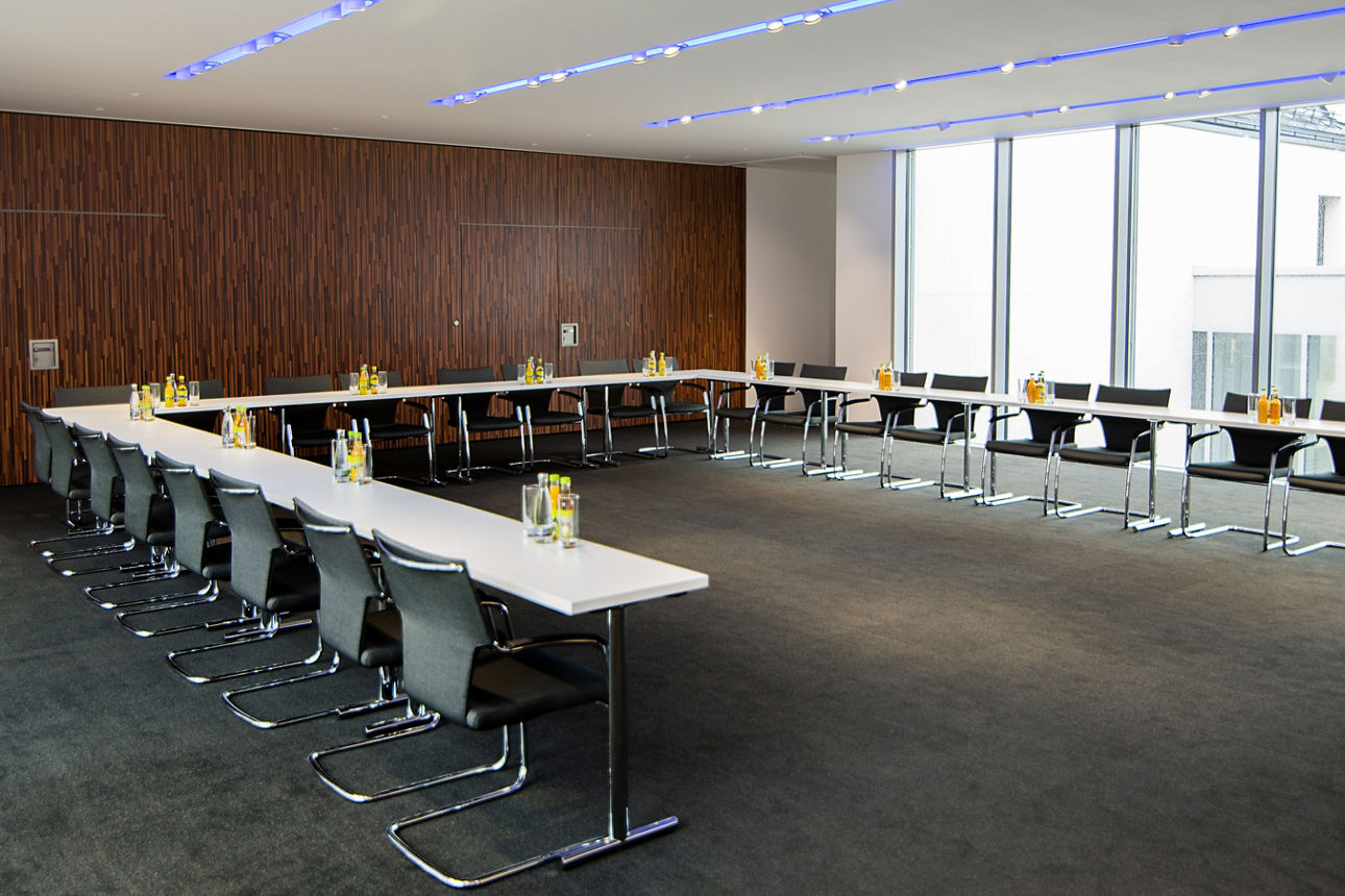 Großer Konferenzraum mit Tischen in U-Form aufgebaut