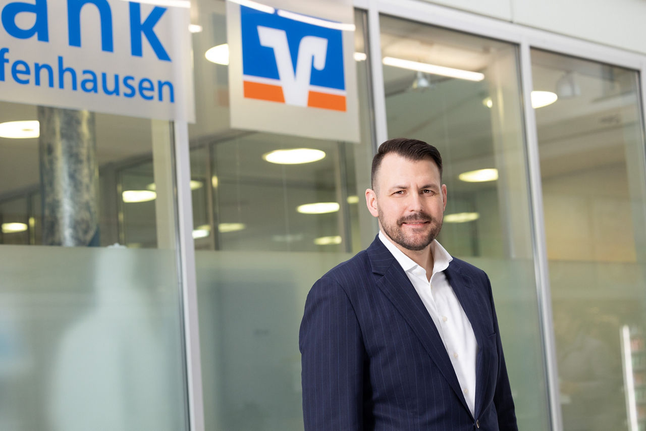 Ein Mann steht lächelnd in vor einer Bankfiliale