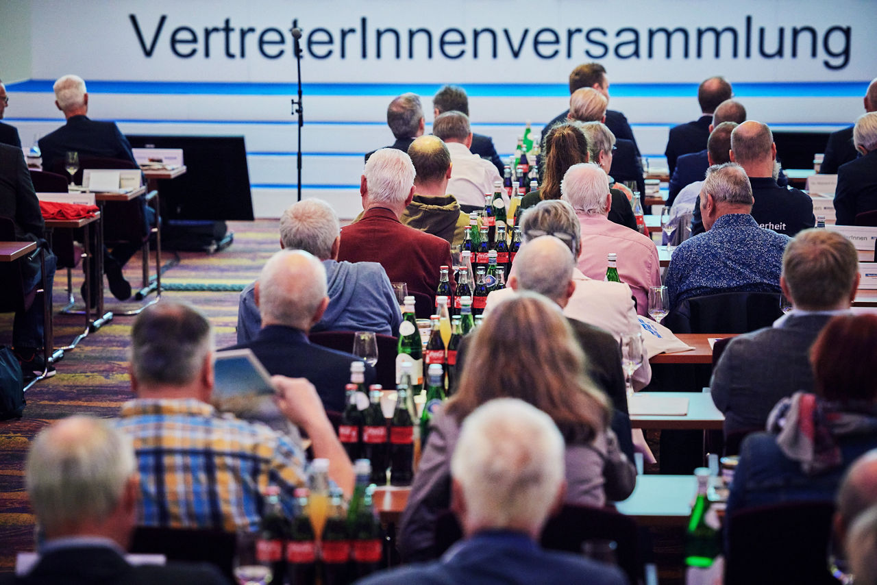 Mehrere Personen sitzen an Tischen auf der VertreterInnenversammlung