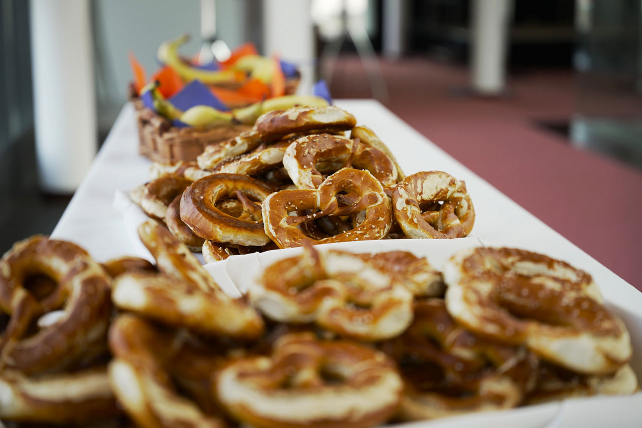 Brezen und Obst stehen schön dekoriert auf einem langen Tisch. 