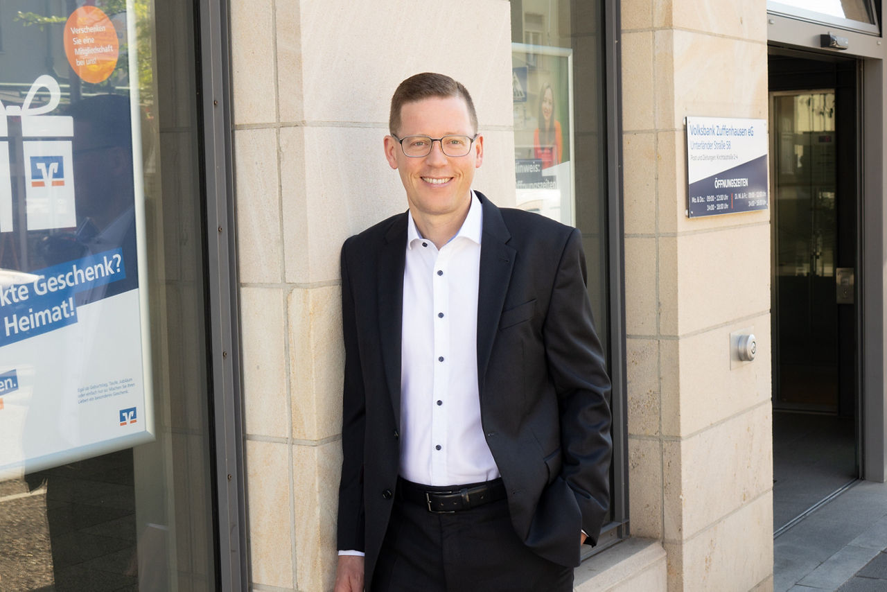 Ein Bankmitarbeiter vor einem Bankgebäude